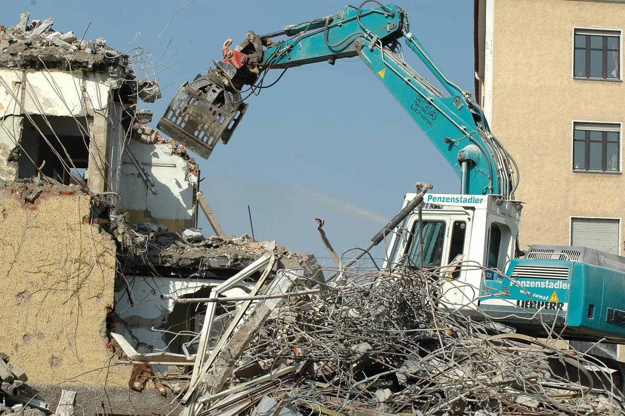 blue excavator demolishing a house